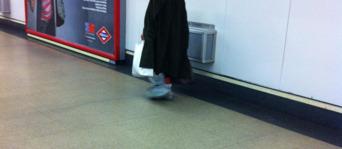 Pobre calzado con bolsas en los pies en el Metro