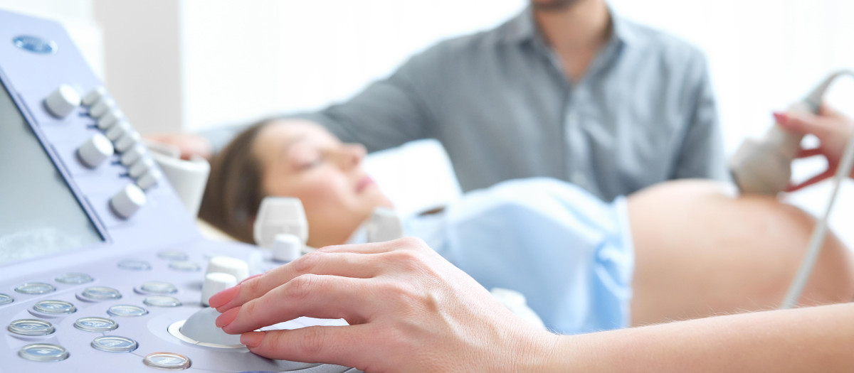 Médico pasando consulta a una mujer embarazada con su marido