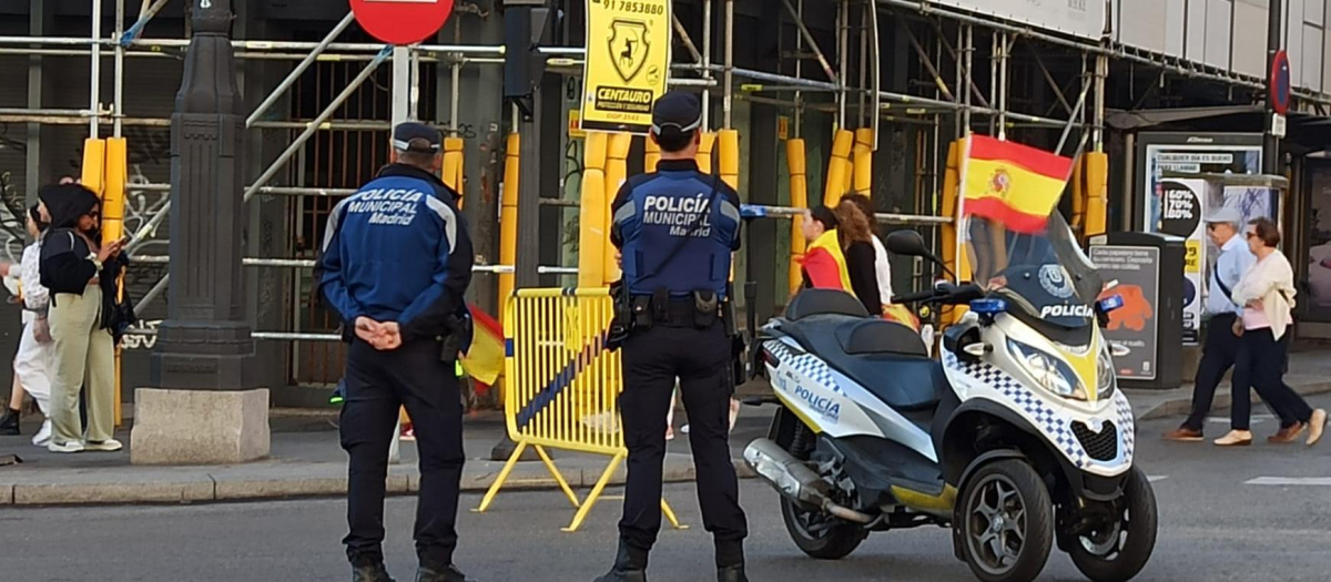 Dos agentes de la Policía Municipal junto a una moto con la bandera de España