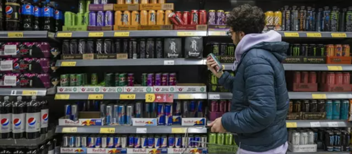 Un joven mira la sección de bebidas energéticas en el supermercado