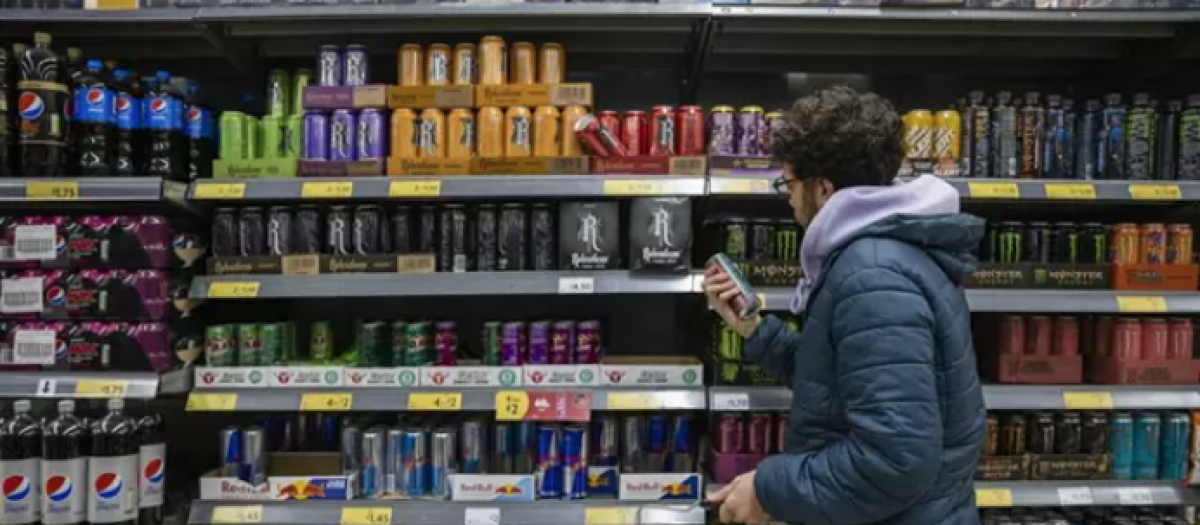 Un joven mira la sección de bebidas energéticas en el supermercado