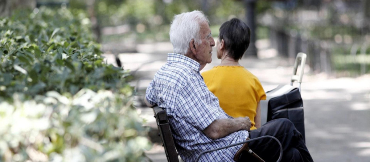 Un pensionista descansa en un banco de un parque de Madrid.