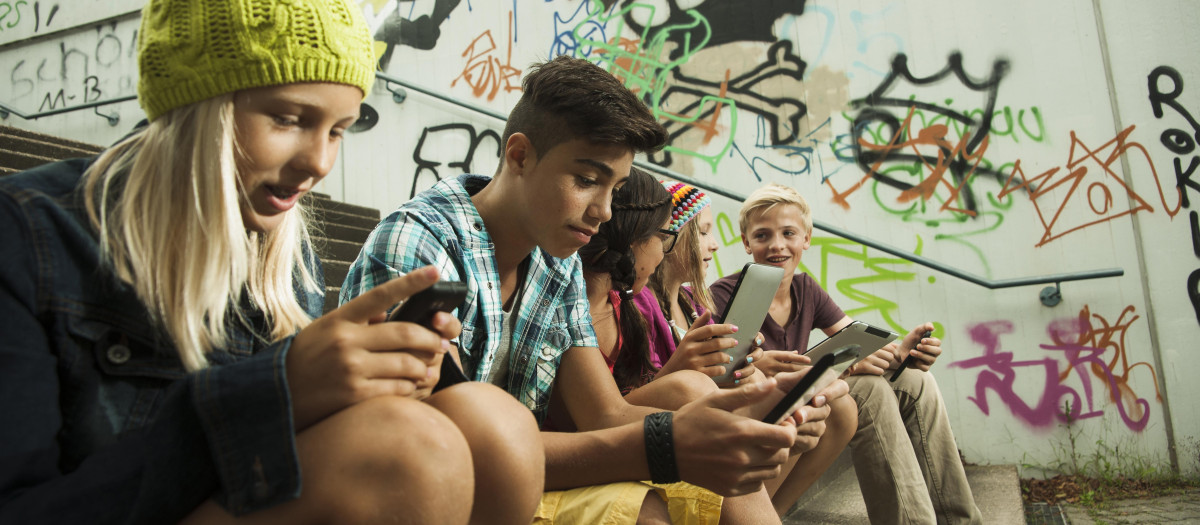 Niños en una escalera, cada uno prestando atención a su móvil
