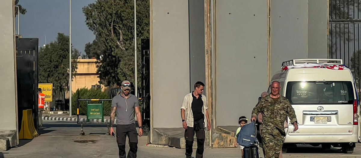 Una mujer y un niño son escoltados después de cruzar el paso fronterizo de Rafah, en Egipto, con la Franja de Gaza