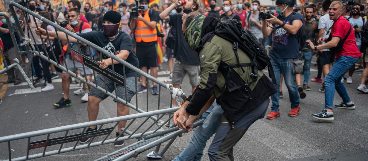 Un hombre arrastra una valla durante unos altercados en la comisaría de la Policía Nacional de la via Layetana
