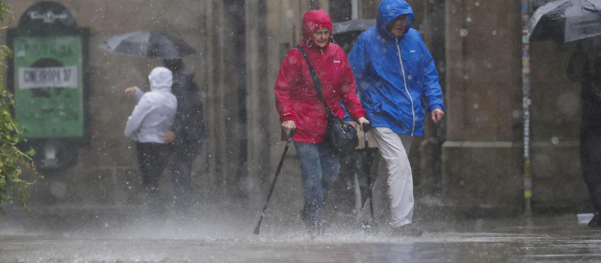 Varias personas con ropa para la lluvia esta mañana en el casco histórico de Santiago de Compostela