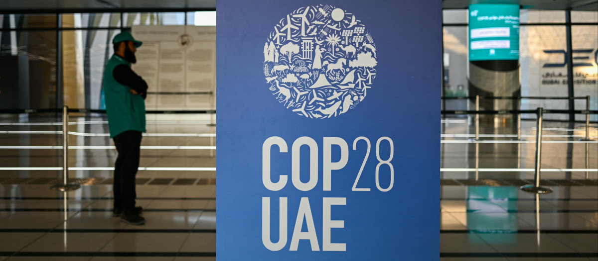 Un hombre cerca de un cartel de la COP28 en una estación de metro de Dubái