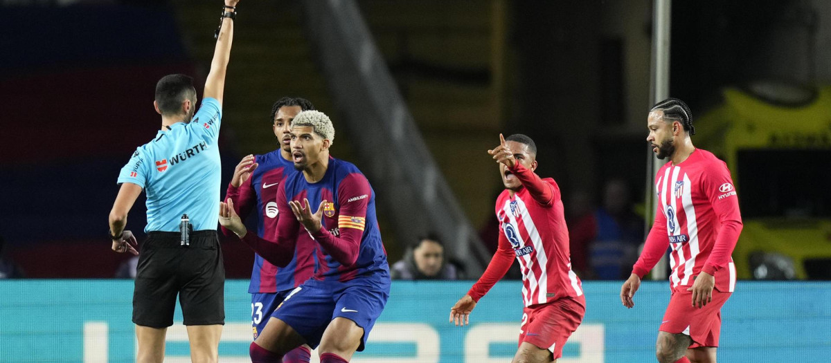 El colegiado Sánchez Martínez sacando una amarilla a Araújo durante el partido frente al Atlético en Montjuic