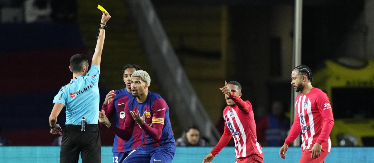 El colegiado Sánchez Martínez sacando una amarilla a Araújo durante el partido frente al Atlético en Montjuic