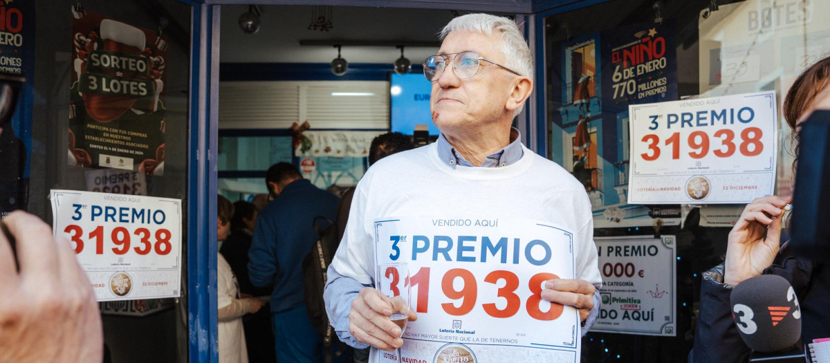 Un hombre sostiene el cartel con el número del tercer premio de la Lotería de Navidad en Biar, Alicante