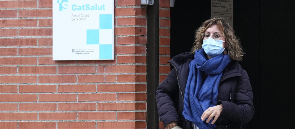 Una mujer sale de un centro de atención primaria con mascarilla