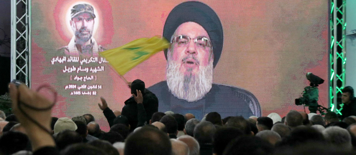 Un hombre ondea una bandera del movimiento Hezbolá mientras su líder, Hassan Nasrallah, pronuncia un discurso televisado