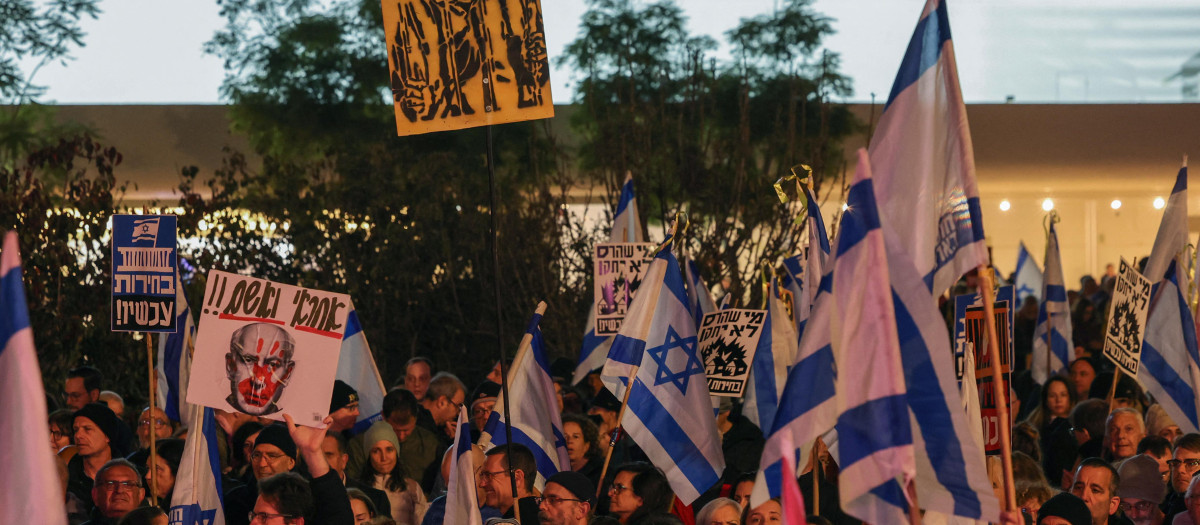 Los manifestantes levantan banderas nacionales y pancartas durante una manifestación en la ciudad central de Tel Aviv,