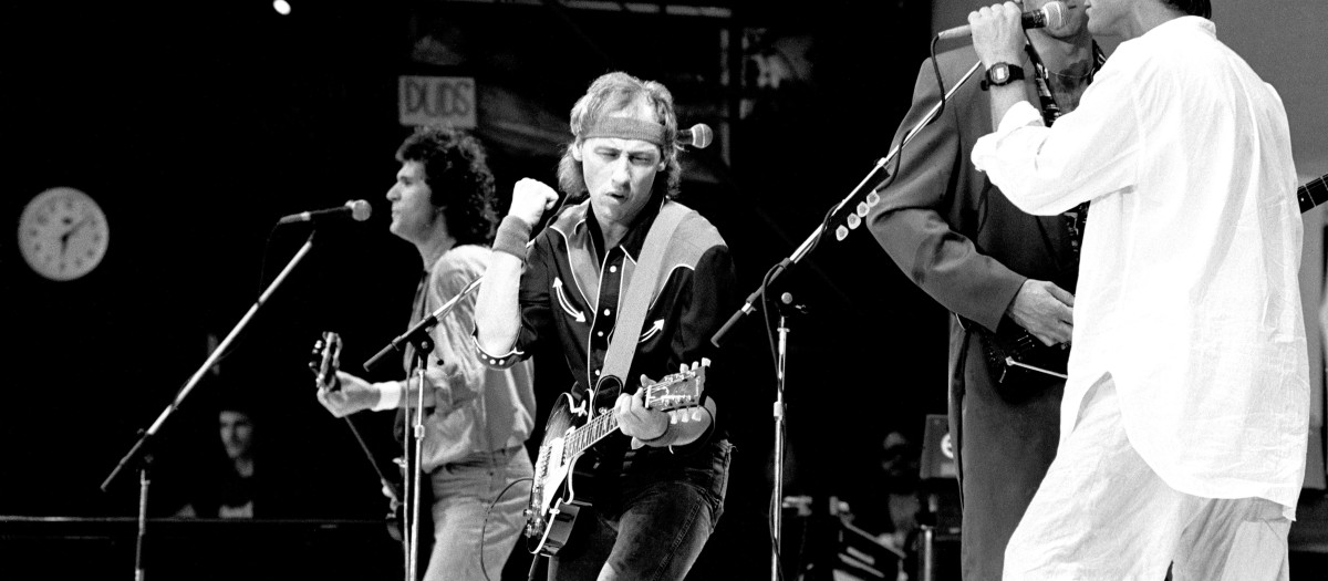Mark Knopfler tocando la guitarra en un concierto de Dire Straits