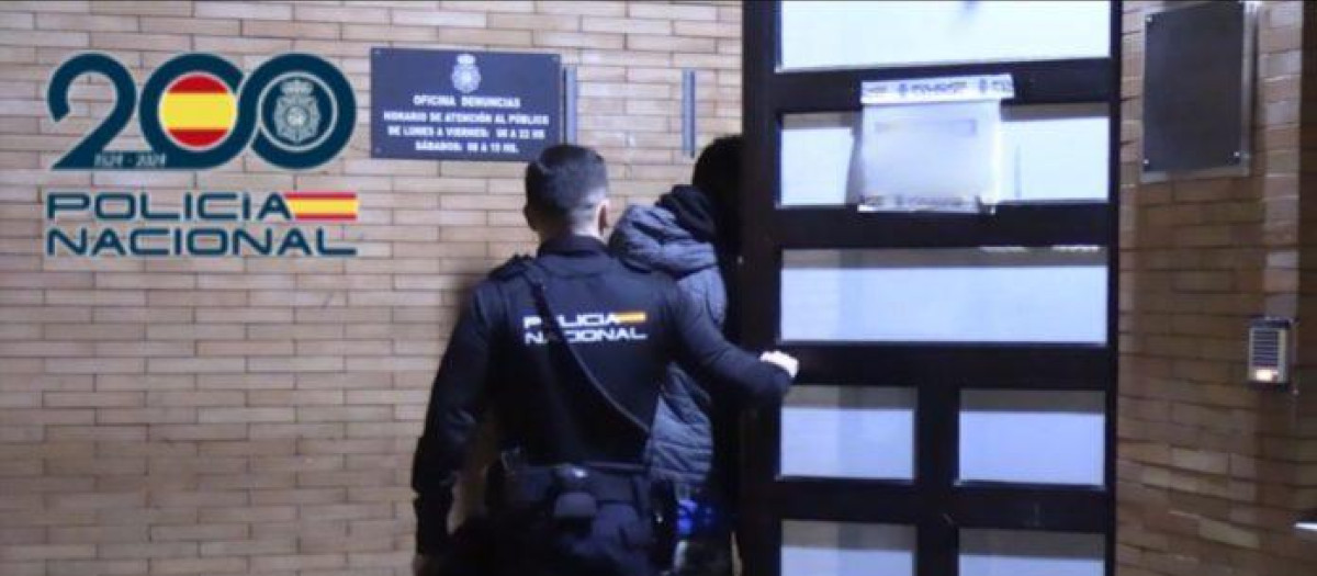 Un agente introduciendo a uno de los detenidos en la comisaría en Alicante