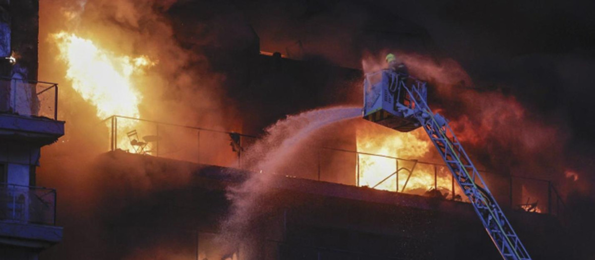 Un bombero subido a una escala lucha contra las llamas en el edificio devorado por las llamas en Valencia
