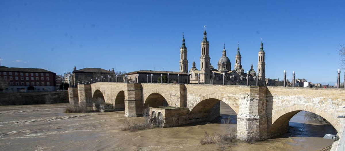 Dos personas observan la crecida del río Ebro a su paso por Zaragoza