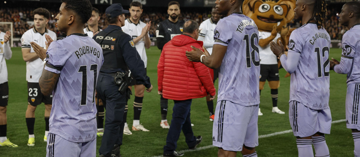 Jugadores del Valencia y el Real Madrid realizan un pasillo de honor a Julián (c), el conserje que ayudó en el desalojo del edificio incendiado de Valencia, y miembros de los cuerpos de seguridad del Estado y servicios de emergencias durante el homenaje recibido antes del partido correspondiente a la jornada 27 de Primera División que Valencia y Real Madrid disputan hoy sábado en el estadio de Mestalla, en Valencia