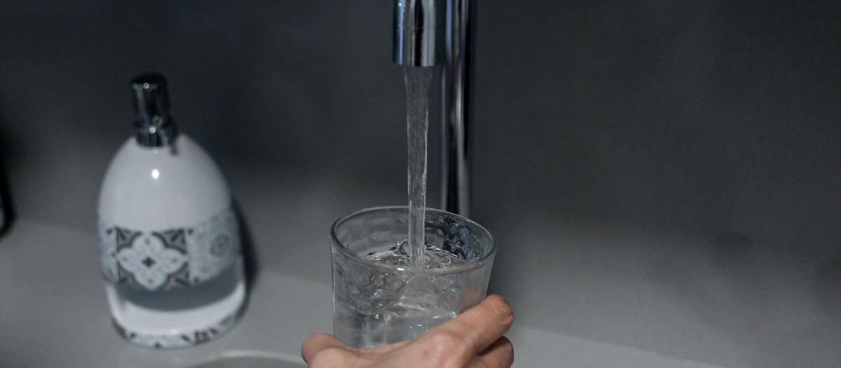 Una persona llena un vaso de agua de un grifo