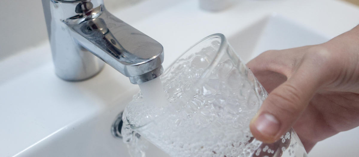 Una persona llena un vaso de agua de un grifo