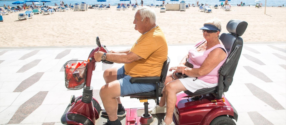 Una pareja pasea en moto eléctrica por el paseo de la playa de Poniente de Benidorm
