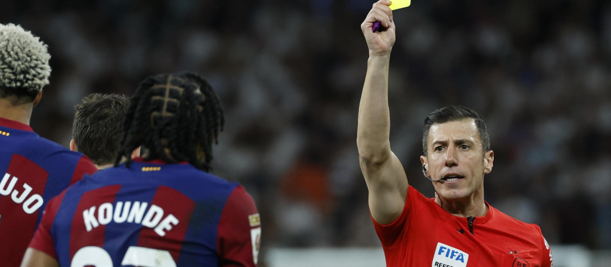 El colegiado saca una tarjeta amarilla durante el partido