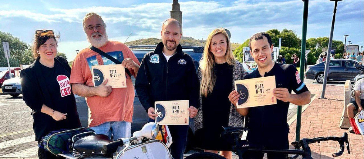 Ruteros de coche, Vespa y bicicleta llegan al pie de la Torre de Hércules con sus diplomas entregados por la concejala coruñesa de turismo Diana Cabanas y Silvia Vázquez por parte de la Ruta N-VI