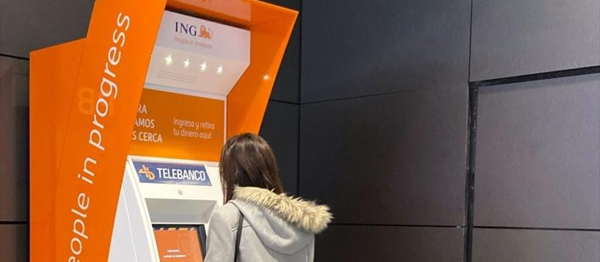 Una mujer saca dinero en un cajero de ING.