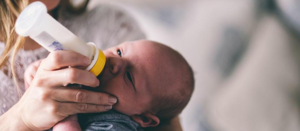 Un bebé bebe leche de un biberón