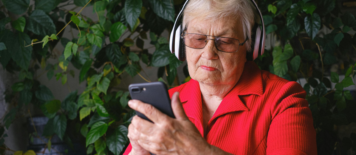 Una mujer con su smartphone y auriculares inalámbricos