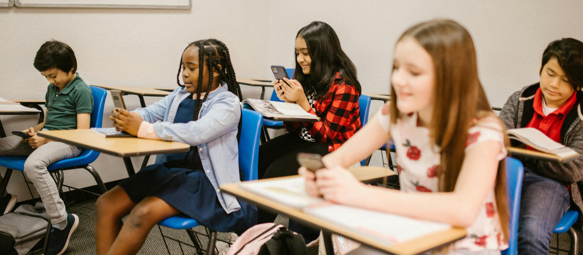 Niños en su aula mirando el móvil