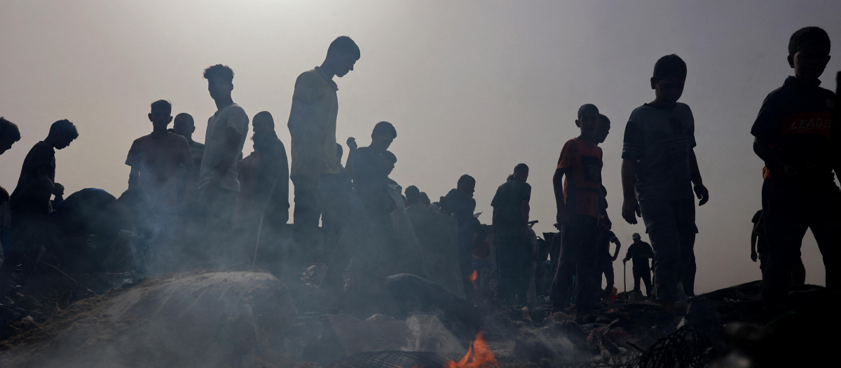 Los palestinos se reúnen en el lugar de un ataque israelí contra un campamento para desplazados internos en Rafah