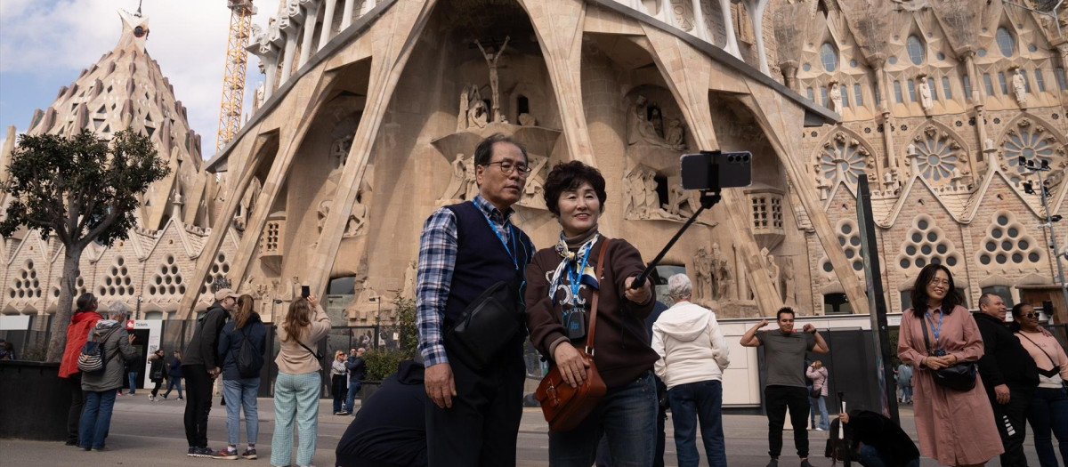 Varios turistas se hacen fotos junto a la Sagrada Familia, en Barcelona.
