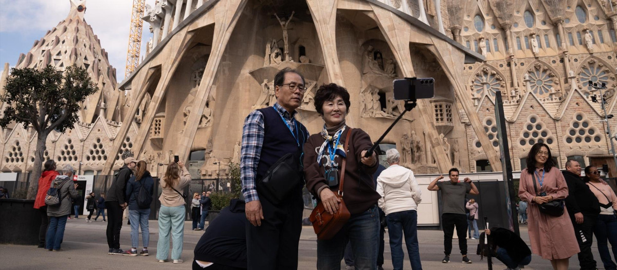 Varios turistas se hacen fotos junto a la Sagrada Familia, en Barcelona.