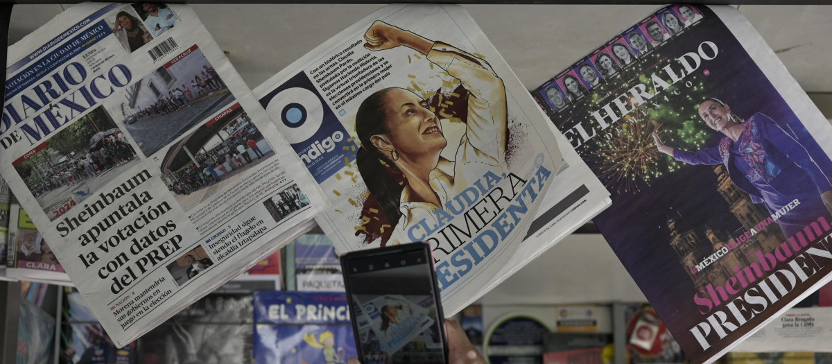 Un transeúnte toma instantáneas con su teléfono móvil de las portadas de los periódicos
