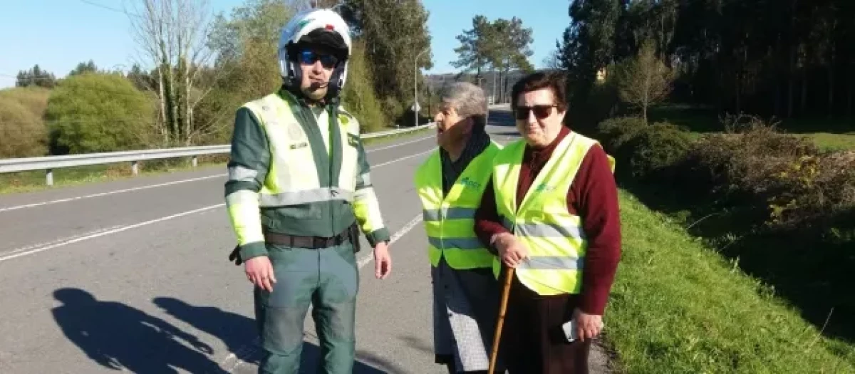 Un Guardia Civil explica a unos peatones el uso del chaleco reflectante