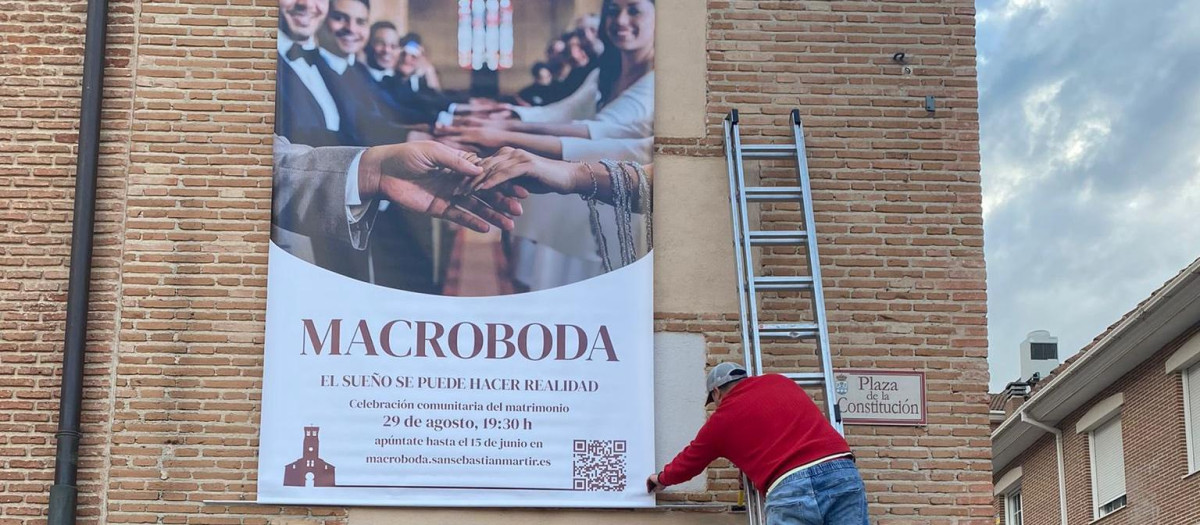 Un operario instala la lona de la "macroboda" en el campanario de la iglesia de San Sebastián