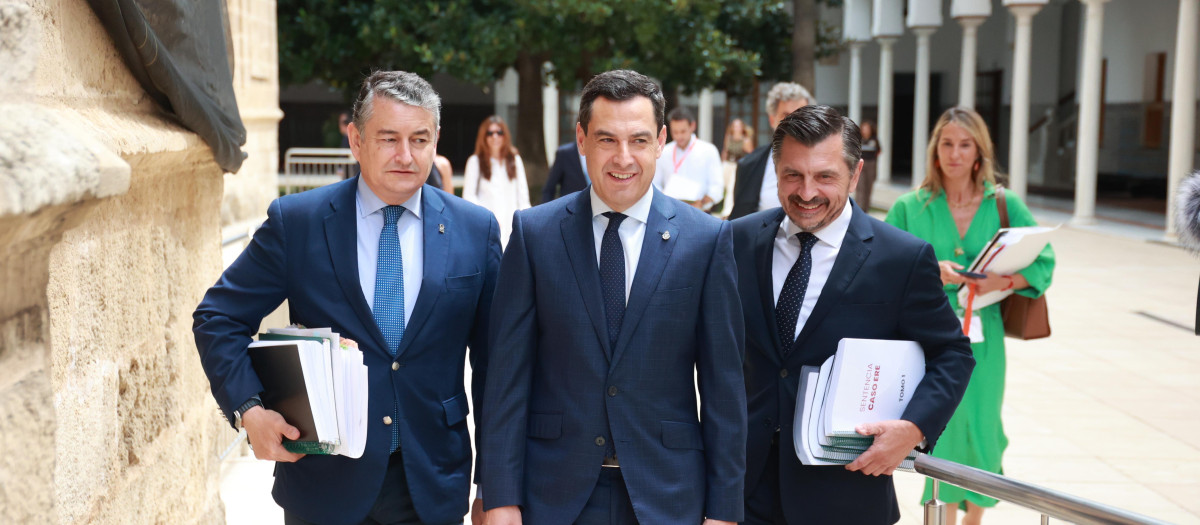 El presidente de la Junta, Juanma Moreno, acompañado del consejero de la Presidencia, Antonio Sanz (izq.), y el portavoz parlamentario del PP andaluz, Toni Martín, con la sentencia del caso ERE bajo el brazo