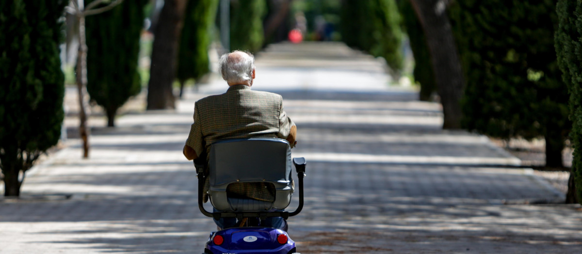 Un anciano en silla de ruedas eléctrica en un parque de Madrid