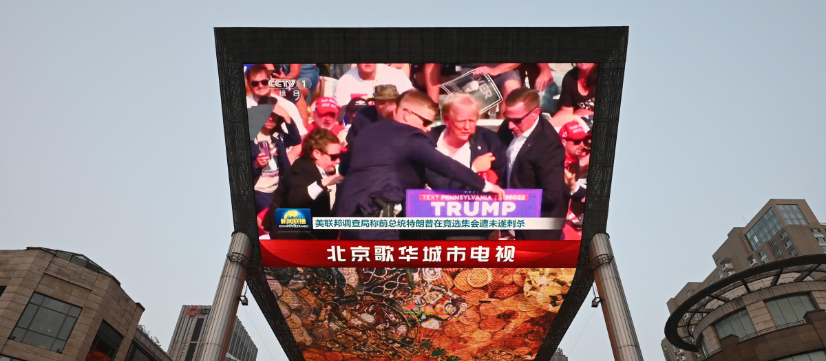 Un programa de noticias sobre el intento de asesinato del expresidente estadounidense Donald Trump se ve en una pantalla gigante en un centro comercial en Pekín