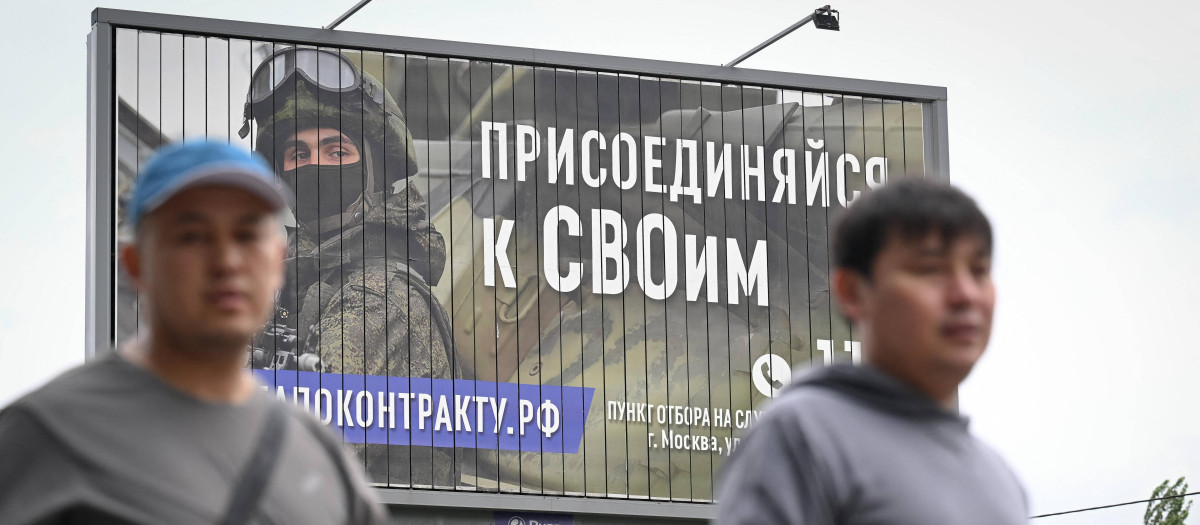 Dos hombres caminan en Moscú bajo un cartel que invita a formar parte del ejército