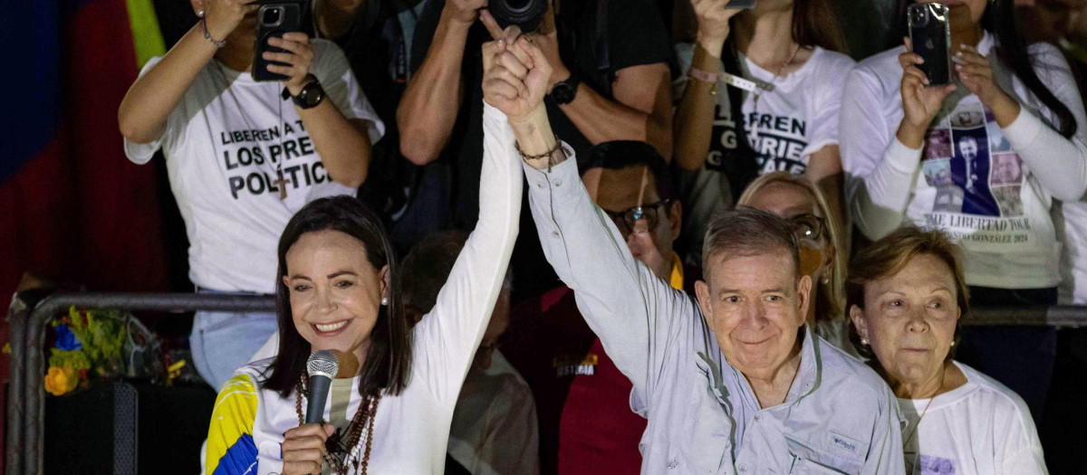 AME4966. CARACAS (VENEZUELA), 25/07/2024.- La líder opositora venezolana, María Corina Machado (i), y el candidato a la presidencia de Venezuela, Edmundo González Urrutia (c), saludan a simpatizantes en el cierre de campaña de González Urrutia, este jueves, en Caracas (Venezuela). González Urrutia pidió a los venezolanos, en un acto de clausura de la campaña electoral, votar el domingo para comenzar el camino de la "reconciliación nacional". EFE/ Ronald Peña R.