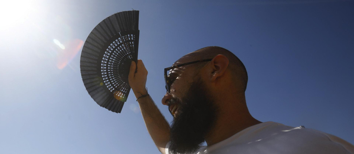 Un turista se protege con un abanico del sol en Córdoba