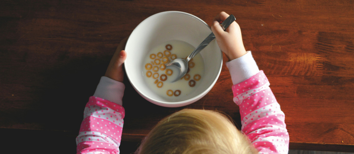Una niña toma un bol de cereales para desayunar