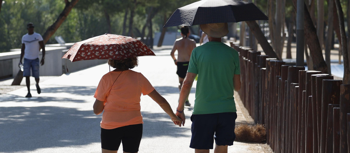 Una pareja pasea protegida por paraguas esta mañana en la que el calor ya aprieta en Madrid. La jornada de este martes en España vuelve a ser de temperaturas significativamente elevadas, especialmente en la mitad sur y nordeste peninsular, con la entrada de un frente atlántico que probablemente dejará chubascos y tormentas localmente fuertes en la Ibérica y Pirineo orientales
