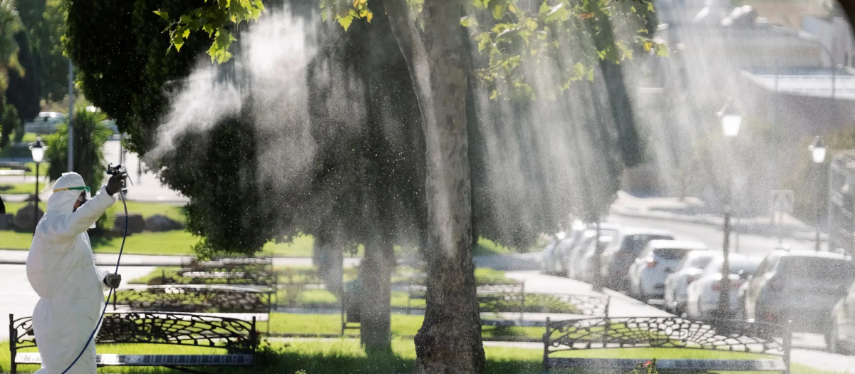 Un operario fumiga unos jardines