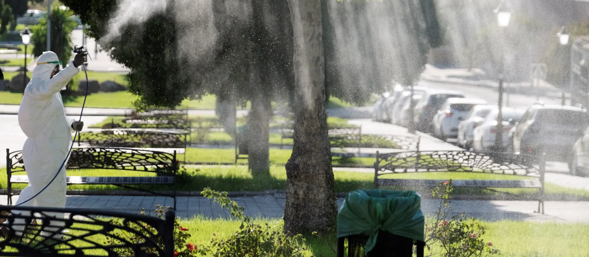 Un operario fumiga unos jardines