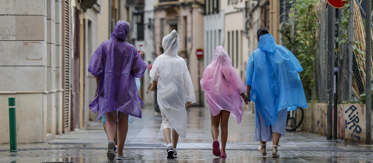 Varias personas caminan bajo la lluvia por una calle del centro de Valencia