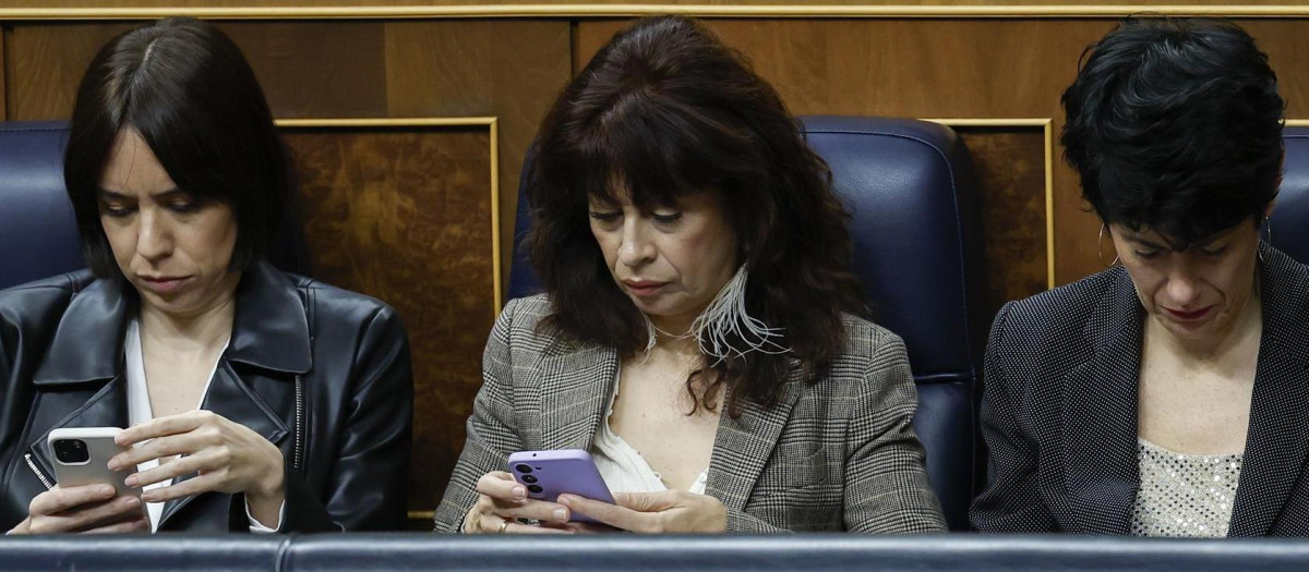 Ana Redondo, en el centro, consulta su teléfono móvil durante una sesión del control al Gobierno