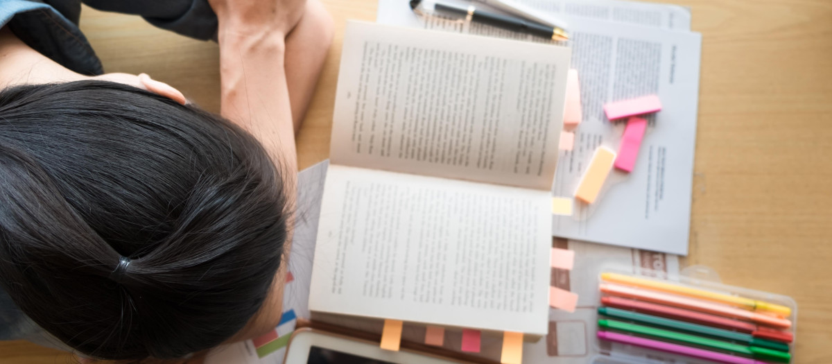 Una estudiante cansada frente a sus libros en la biblioteca